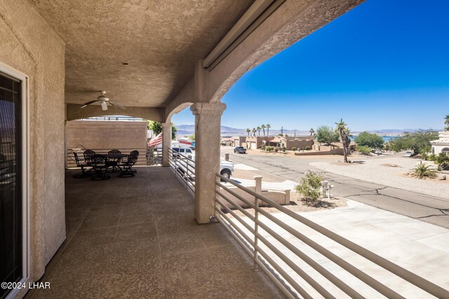 view of patio featuring ceiling fan, a mountain view, and a balcony