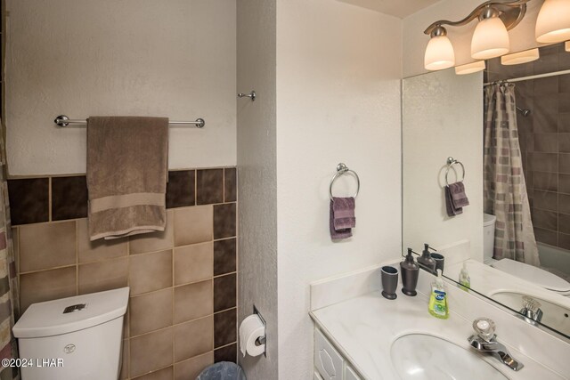 full bathroom featuring a shower with shower curtain, vanity, tile walls, and toilet