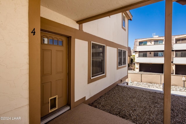 view of exterior entry with stucco siding and fence