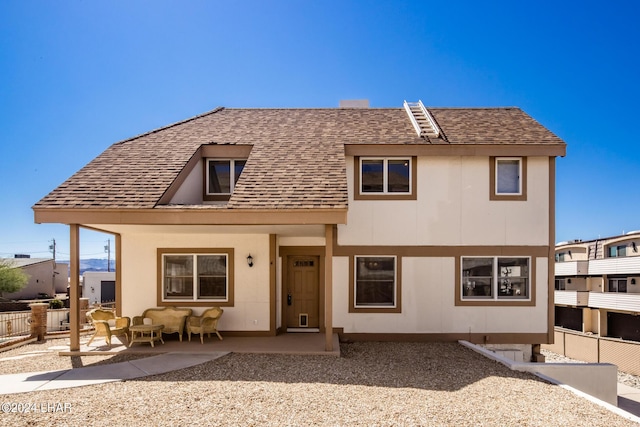 rear view of property with a patio area, fence, and a shingled roof