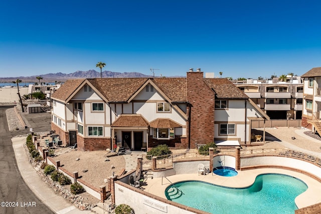 community pool with a patio area, a residential view, a fenced backyard, and a mountain view