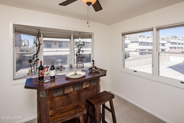 bar featuring a bar, carpet, baseboards, and ceiling fan