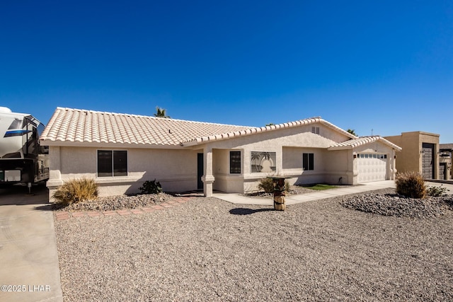 view of front of property featuring a garage, a tiled roof, concrete driveway, and stucco siding