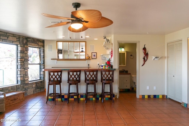 kitchen with tile patterned flooring, a breakfast bar area, and ceiling fan