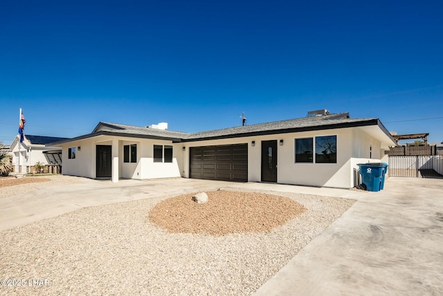 ranch-style home with a garage, fence, concrete driveway, and stucco siding