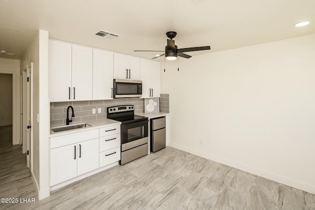 kitchen with appliances with stainless steel finishes, light countertops, a sink, and tasteful backsplash