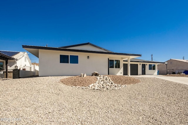 exterior space featuring a garage, fence, driveway, and stucco siding