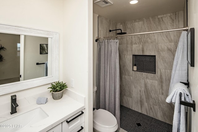 bathroom with toilet, vanity, a tile shower, and visible vents