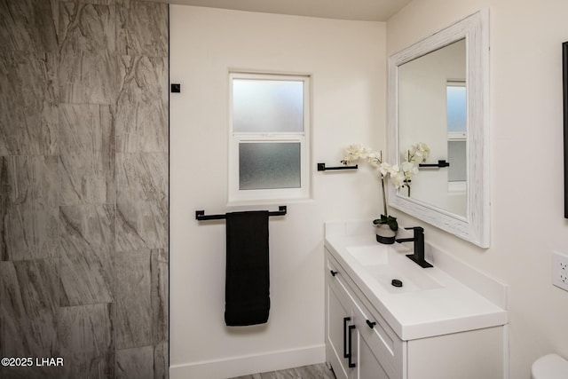 bathroom featuring toilet, baseboards, and vanity