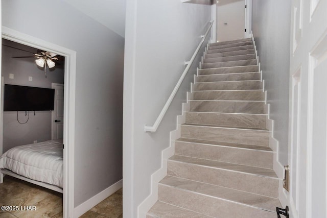 stairway featuring baseboards and a ceiling fan