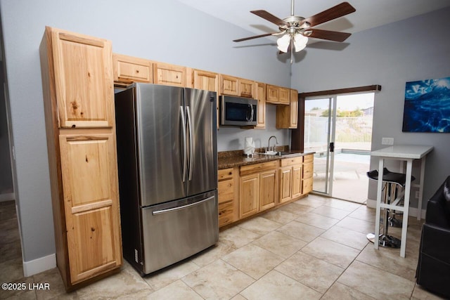 kitchen with light tile patterned floors, ceiling fan, a sink, appliances with stainless steel finishes, and dark countertops