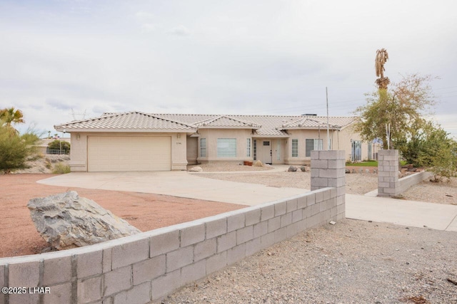 view of front of property with fence, stucco siding, concrete driveway, a garage, and a tiled roof