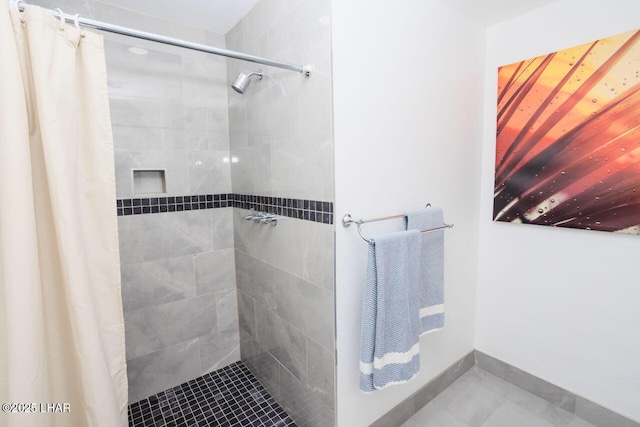 full bath with baseboards and a tile shower