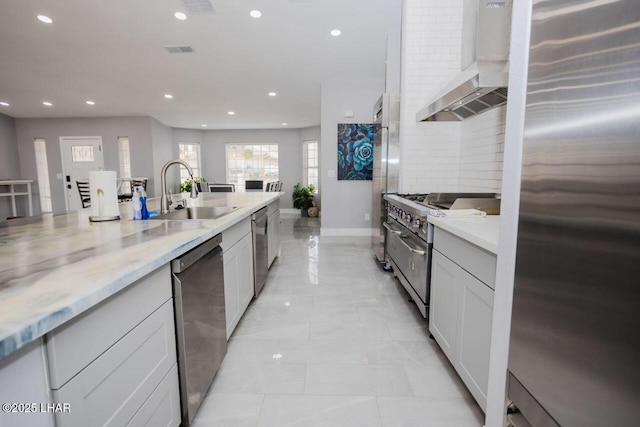 kitchen featuring visible vents, recessed lighting, a sink, appliances with stainless steel finishes, and wall chimney range hood