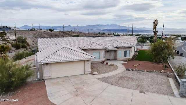 view of front of home with stucco siding, a garage, a mountain view, and a tiled roof