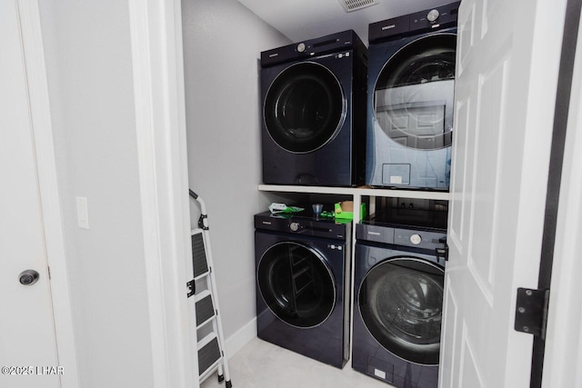 laundry area with laundry area, visible vents, stacked washing maching and dryer, and baseboards