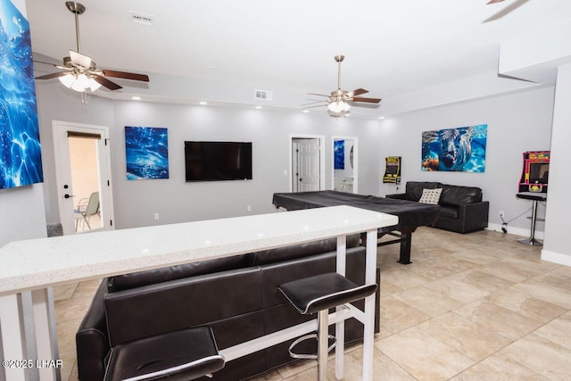 living area featuring visible vents, baseboards, and ceiling fan