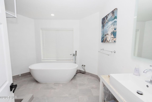 full bath featuring recessed lighting, baseboards, a freestanding bath, and vanity