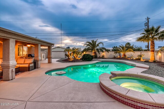 pool at dusk with an in ground hot tub and a patio area