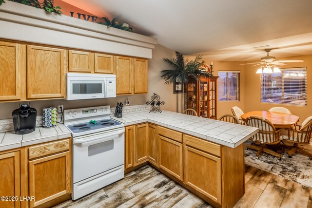 kitchen featuring tile counters, white appliances, ceiling fan, kitchen peninsula, and light wood-type flooring