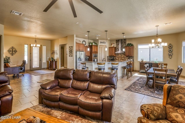 living room with ceiling fan with notable chandelier, sink, a textured ceiling, and a wealth of natural light