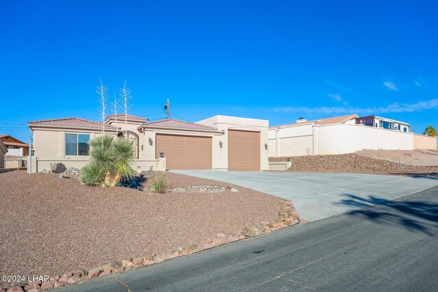 2555 Avalon Ln, Lake Havasu City, AZ 86404 - view of front of home featuring concrete driveway, a garage, fence, stucco siding, and a tiled roof