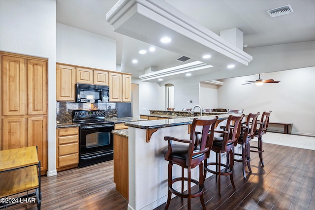 2555 Avalon Ln, Lake Havasu City, AZ 86404 - kitchen featuring black appliances, dark wood-style floors, a breakfast bar, backsplash, and dark stone counters