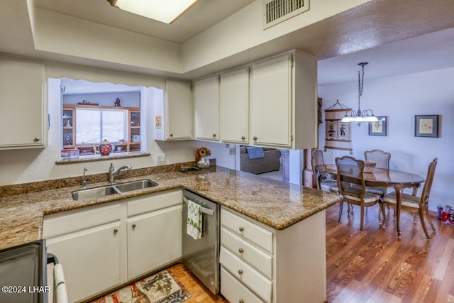 kitchen featuring pendant lighting, sink, light hardwood / wood-style flooring, white cabinets, and stainless steel dishwasher