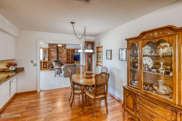 dining space featuring a wood stove, a chandelier, and light hardwood / wood-style floors