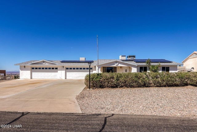 ranch-style house with a garage and solar panels