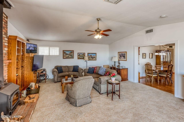 carpeted living room featuring ceiling fan, lofted ceiling, and a wood stove