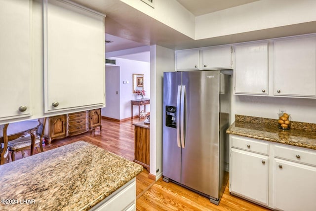 kitchen featuring dark stone countertops, light hardwood / wood-style floors, white cabinets, and stainless steel refrigerator with ice dispenser