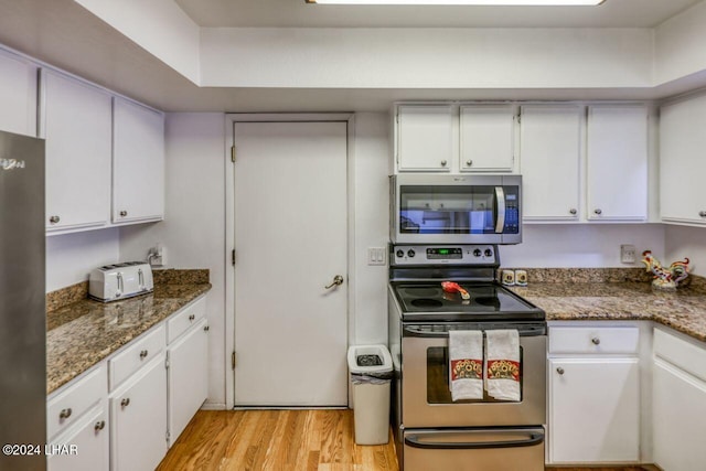 kitchen featuring white cabinetry, light hardwood / wood-style floors, dark stone countertops, and appliances with stainless steel finishes