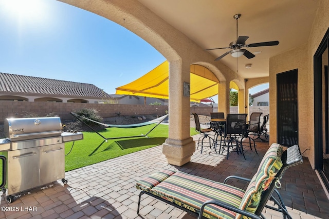 view of patio with a fenced backyard, a grill, ceiling fan, and outdoor dining area