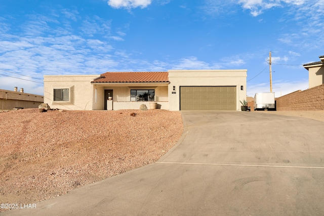 adobe home with a tile roof, driveway, an attached garage, and stucco siding