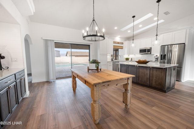 kitchen with tasteful backsplash, visible vents, vaulted ceiling, stainless steel appliances, and light countertops