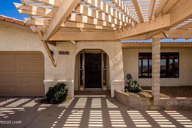 entrance to property with a garage and a pergola