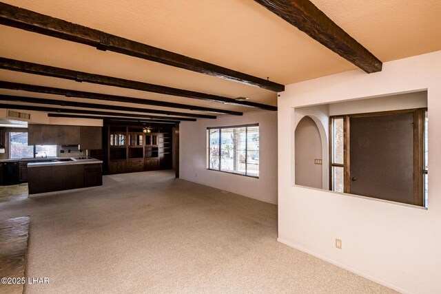 carpeted empty room with beam ceiling