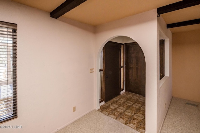 hall with light colored carpet and beam ceiling