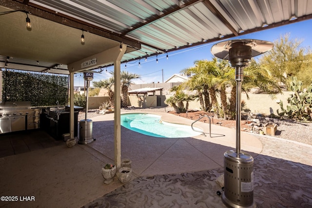 view of pool featuring area for grilling, a fenced backyard, exterior kitchen, and a patio