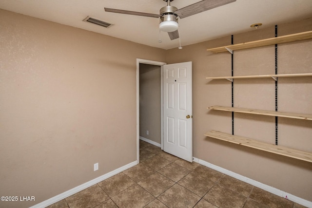 empty room with visible vents, tile patterned floors, baseboards, and ceiling fan
