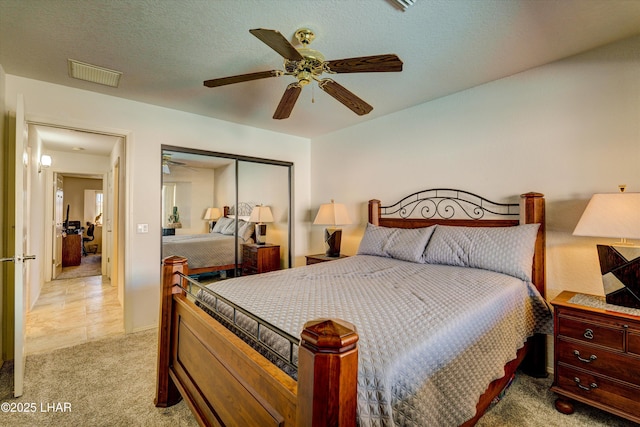 carpeted bedroom featuring ceiling fan, a closet, and a textured ceiling