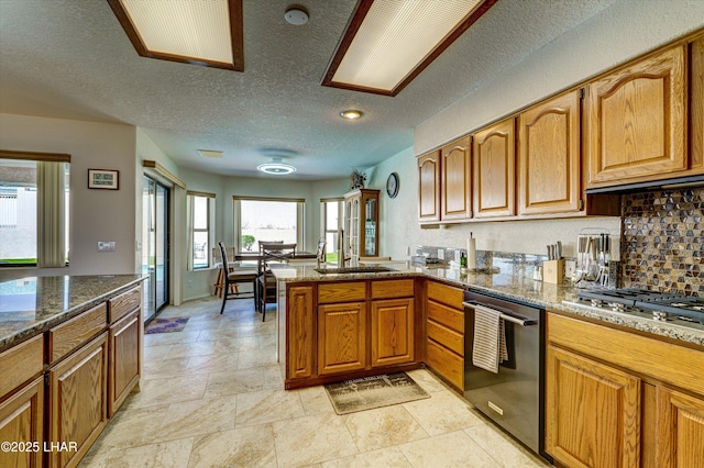 kitchen with sink, tasteful backsplash, stone countertops, kitchen peninsula, and stainless steel appliances