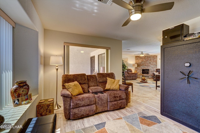 living room featuring a brick fireplace, hardwood / wood-style floors, and ceiling fan