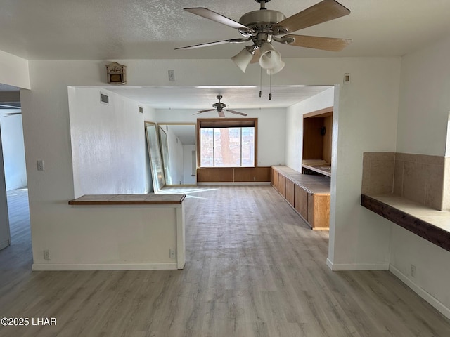 interior space featuring ceiling fan, a textured ceiling, and light wood-type flooring