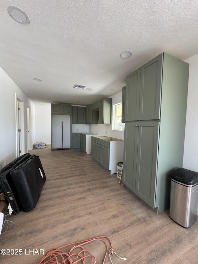 31567 94th St, Parker, AZ 85344 - kitchen with green cabinetry, light wood-style floors, and a textured ceiling