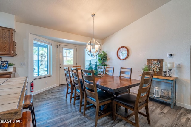 dining space featuring dark hardwood / wood-style flooring, vaulted ceiling, and an inviting chandelier