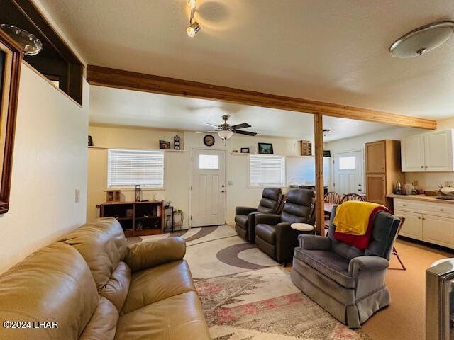 living room with light carpet, ceiling fan, and beamed ceiling