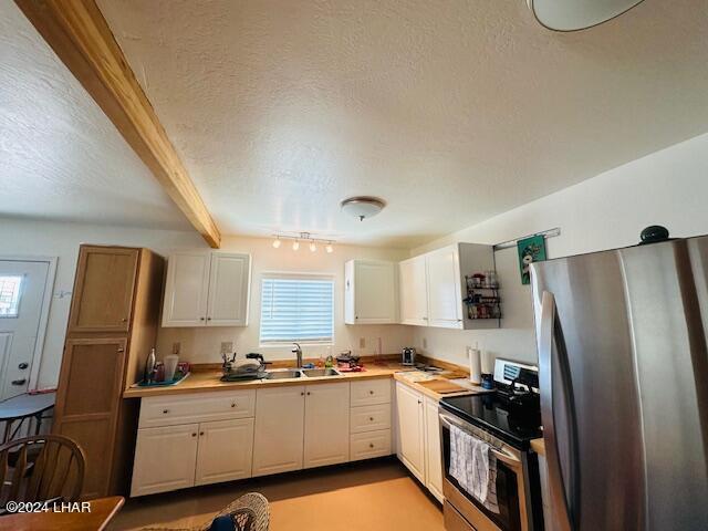 kitchen featuring white cabinetry, beam ceiling, stainless steel appliances, and a textured ceiling