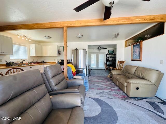 carpeted living room with french doors, ceiling fan, and beam ceiling